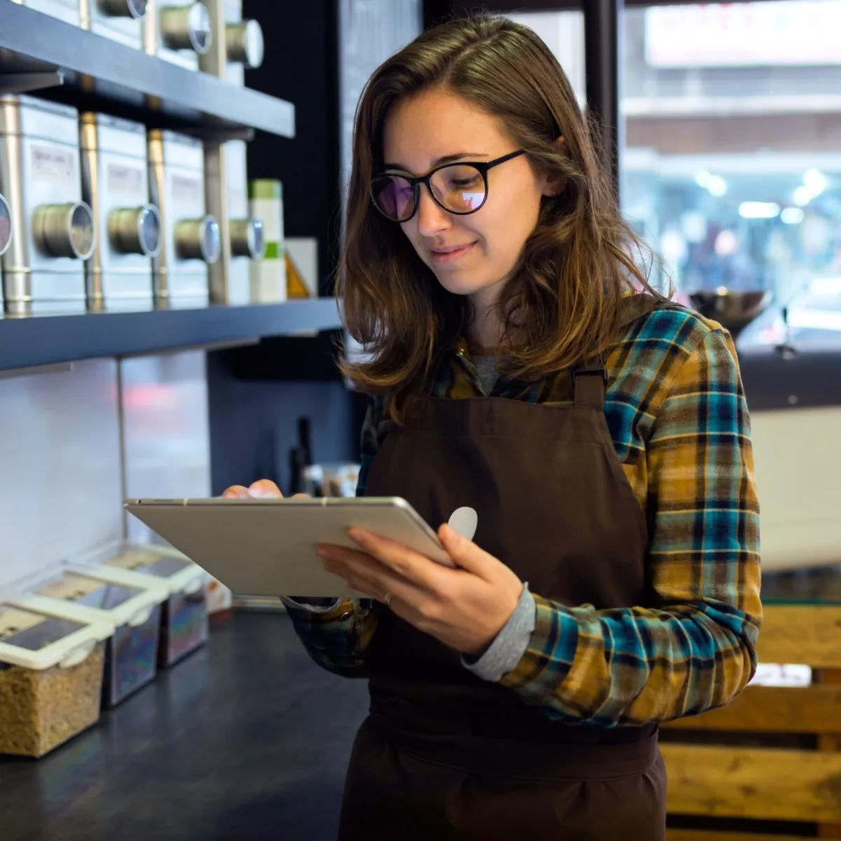 Einzelhandel und Verkauf Mitarbeiterin in einem Café mit Tablet – Café-Angestellte überprüft Bestellungen, Beispiel für Personal im Gastgewerbe.